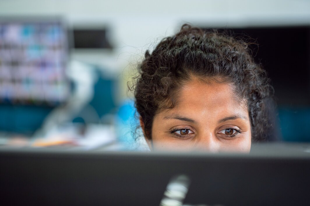 Eine Frau schaut lächeln auf einen PC Bildschirm