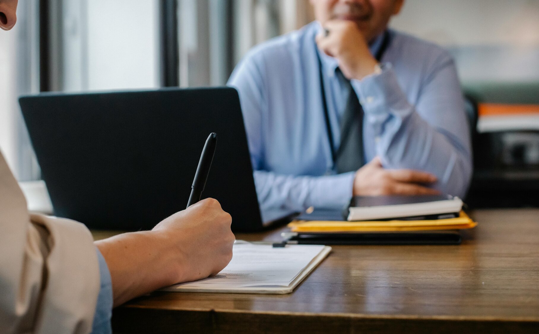 Eine Person interviewt eine andere Person und schreibt mit.