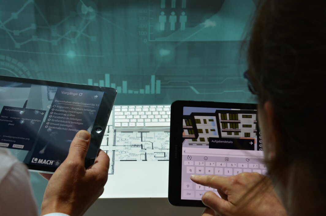 Augmented Reality Bauplan eines Hauses hinter zwei Personen mit Tablets