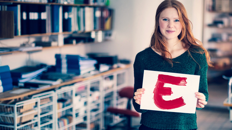 Mitarbeiterin in der öffentlichen Verwaltung präsentiert ein Schild mit "E" für E-Beschaffung