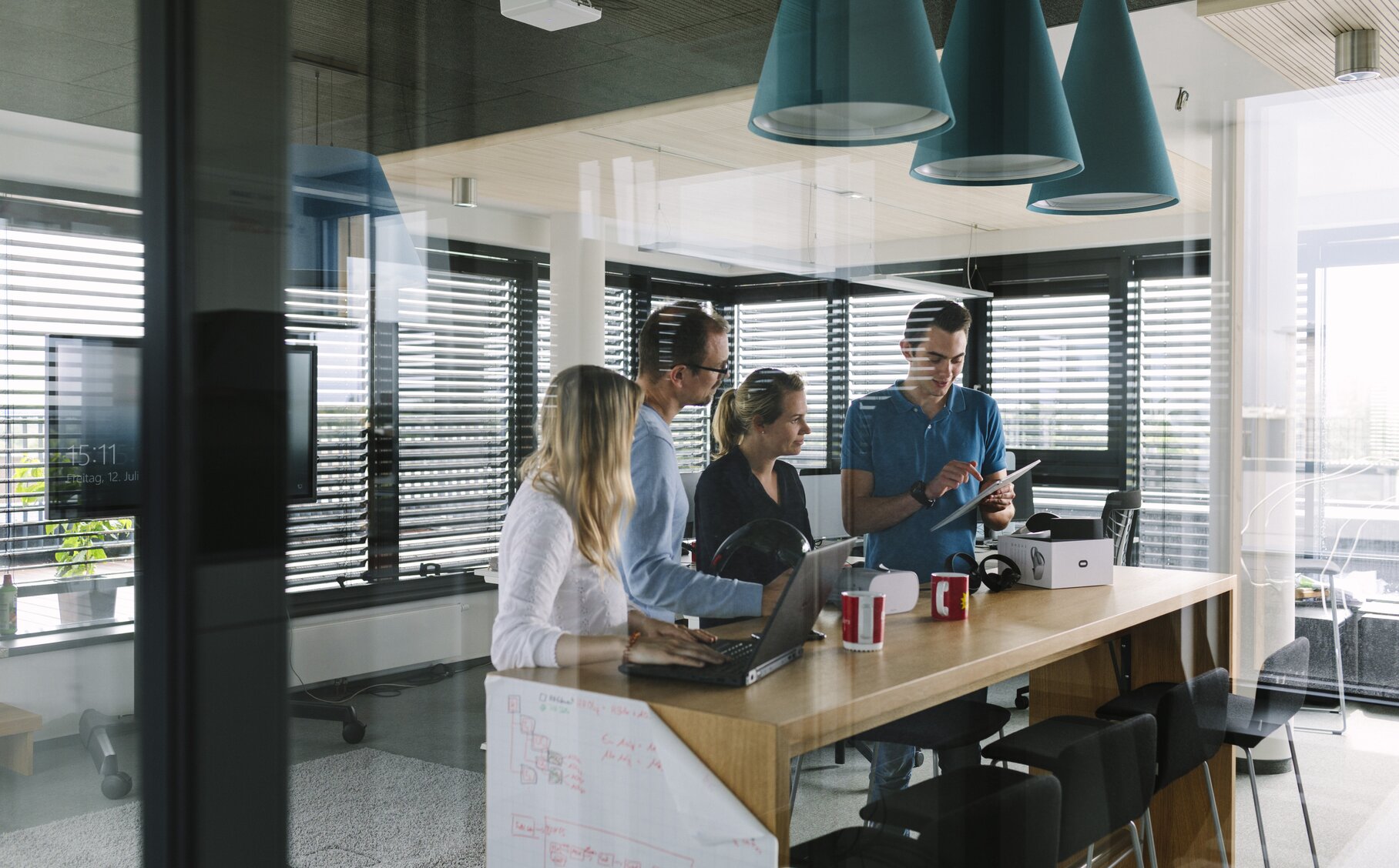 Vier Mitarbeiter schauen sich etwas auf einem Tablet an.