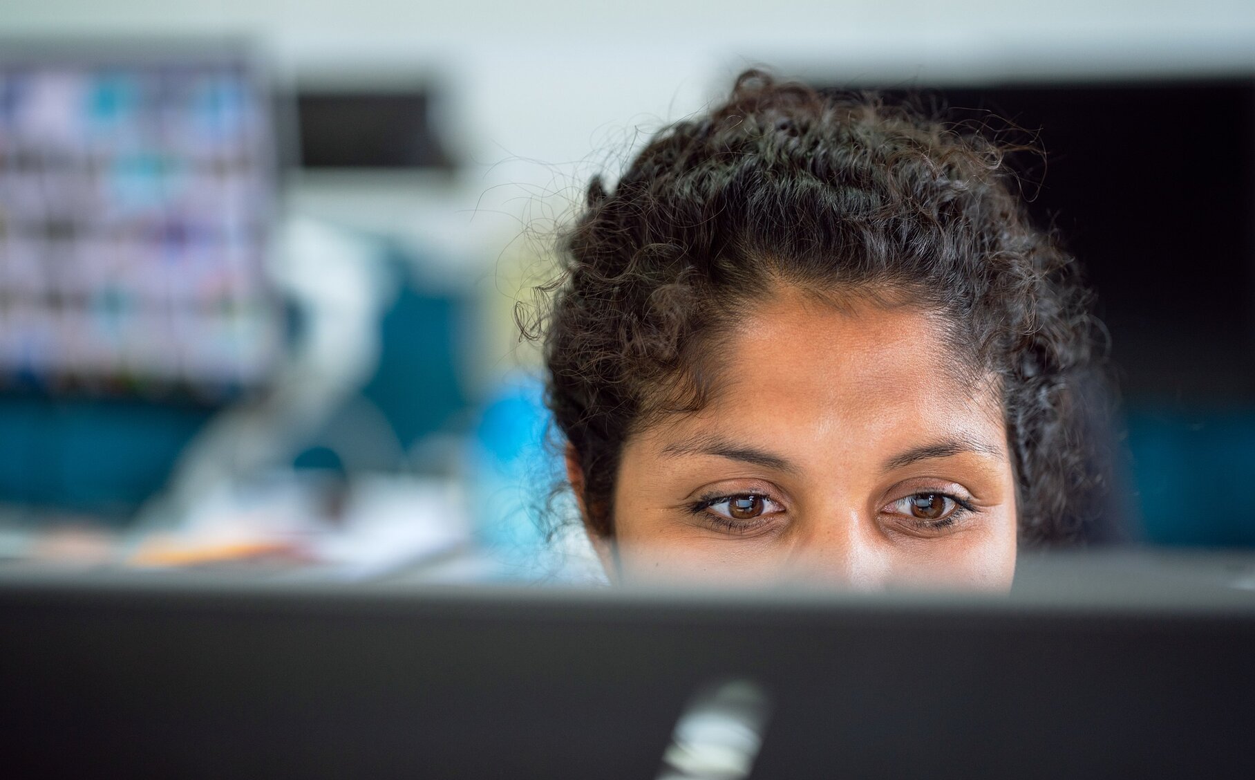Eine Frau schaut lächeln auf einen PC Bildschirm