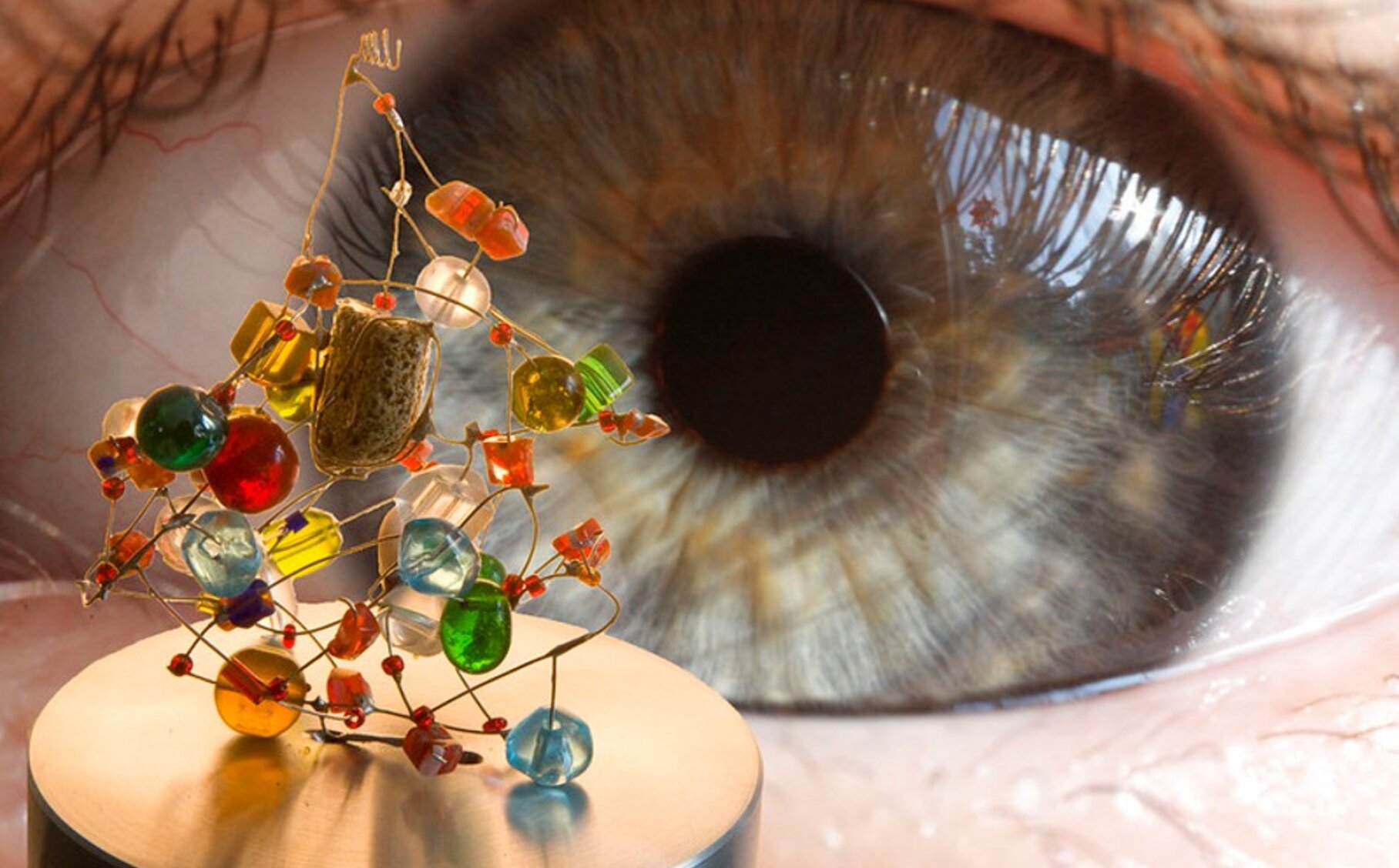 Ein Auge betrachtet eine winzige Figur komplexer Formen und Farben. | © Komplexe Systemarchitekturen mit MACH verstehen