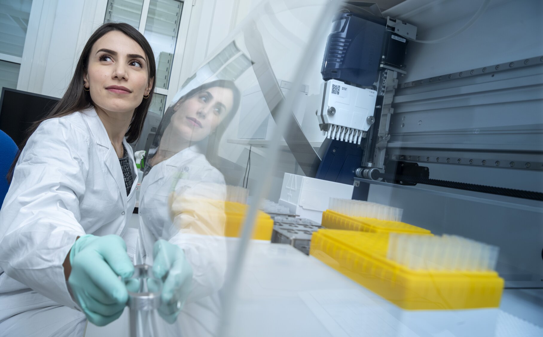 Mitarbeiterin des DIfE arbeitet mit Kittel und Handschuhen im Labor. | © David Ausserhofer