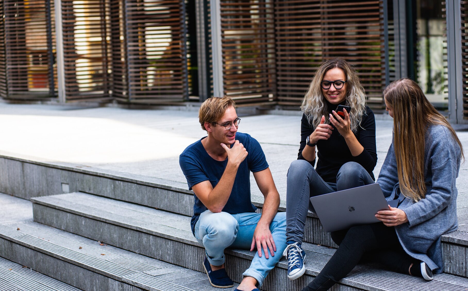 Drei Personen die auf einer Treppe sitzen und miteinander reden