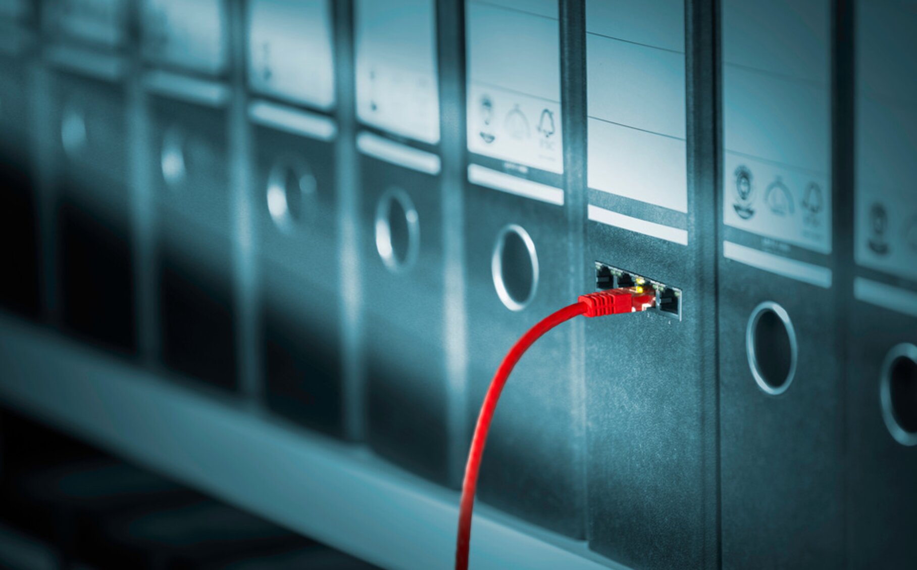 Eine Reihe von Akten. Aus einer Akte ragt ein Kabel.