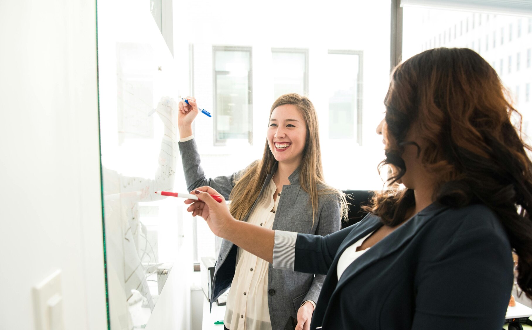 Zwei Frauen notieren Dinge auf einer Tafel.