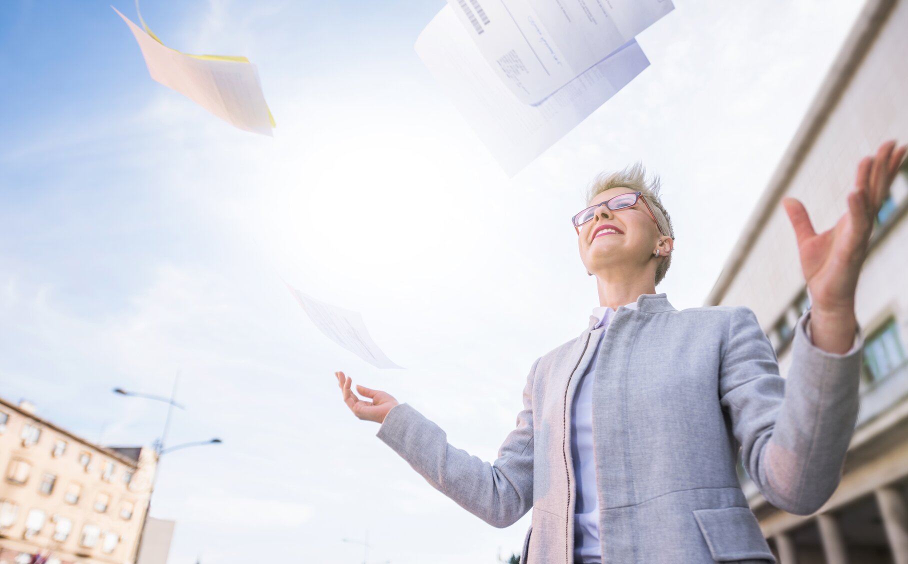 Eine Mitarbeiterin der öffentlichen Verwaltung wirft glücklich Dokumente in die Luft